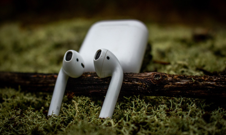 Closeup Of Airpods With Charging Case In The Back